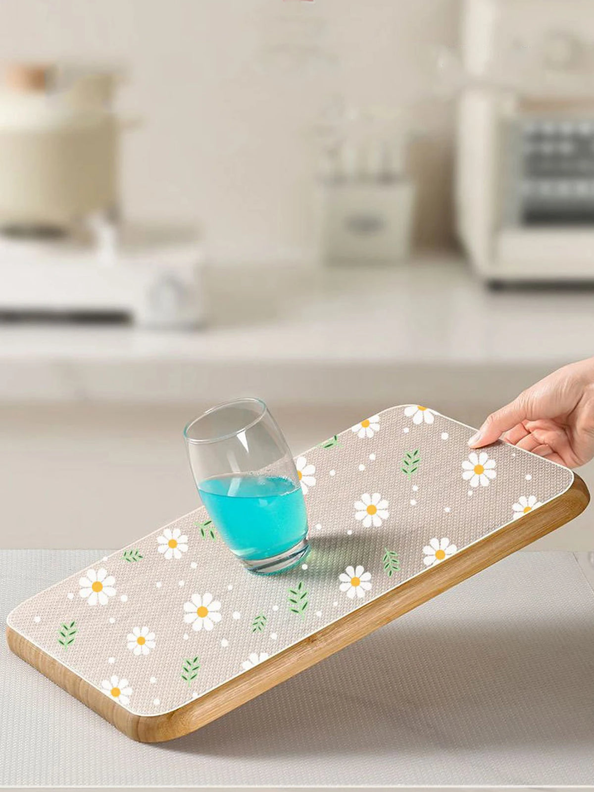 A wooden drawer mat with a floral pattern is shown under a glass of blue liquid.