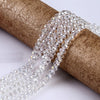 Clear faceted crystal glass spacer beads coiled on a brown cylindrical object for jewelry making