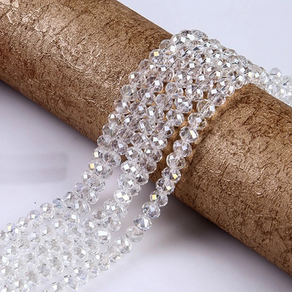 Clear faceted crystal glass spacer beads coiled on a brown cylindrical object for jewelry making