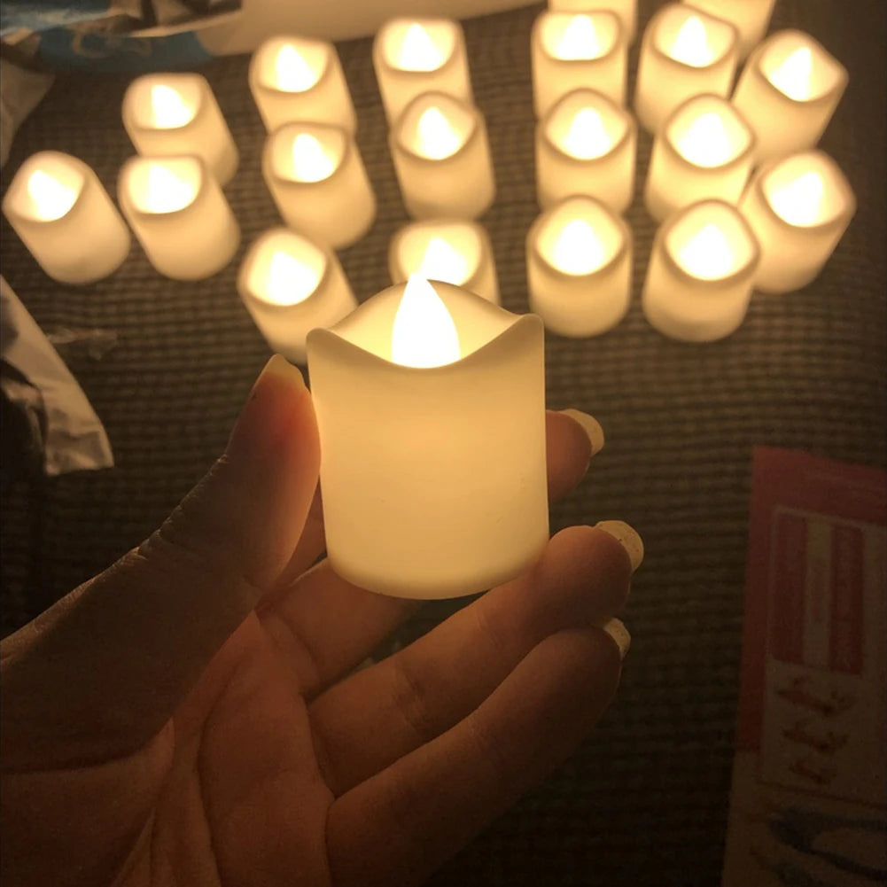 A hand holds a glowing white LED tea light candle, surrounded by other similar lights.