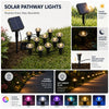 A set of solar pathway lights illuminating a garden path at night.