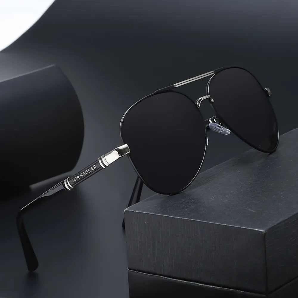 A pair of black classic aviator sunglasses with silver detailing resting on a dark surface.