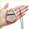 A hand holds a mini 8-key kalimba thumb piano made of wood and metal keys.