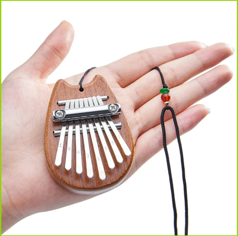 A hand holds a mini 8-key kalimba thumb piano made of wood and metal keys.
