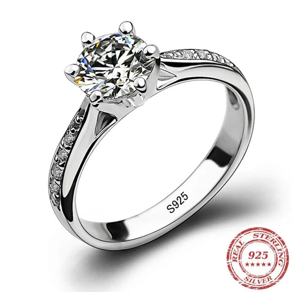 A sterling silver ring featuring a round brilliant-cut diamond with zircon accents on the head and pave diamonds along the ba