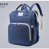 A navy blue backpack diaper bag featuring a zippered compartment and a light beige changing mat.