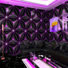 A modern living room decorated with black geometric luminous wallpaper and a black leather sofa.