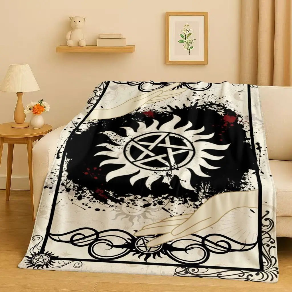 A black and white graphic throw blanket featuring a sun design and occult symbols.