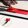 A hand is using a red paint edge trimmer with a rotatable handle to apply paint on a surface.