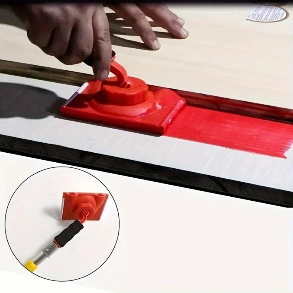 A hand is using a red paint edge trimmer with a rotatable handle to apply paint on a surface.