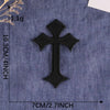 A black embroidered cross patch on a blue denim fabric background.