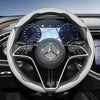 Close-up view of a black steering wheel with a carbon fiber texture cover and Mercedes-Benz instrument cluster.