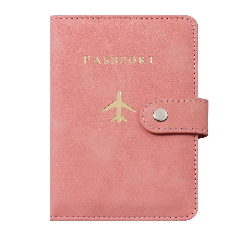 Porte-passeport en cuir rose avec texte gravé en or et emblème d'avion doré.
