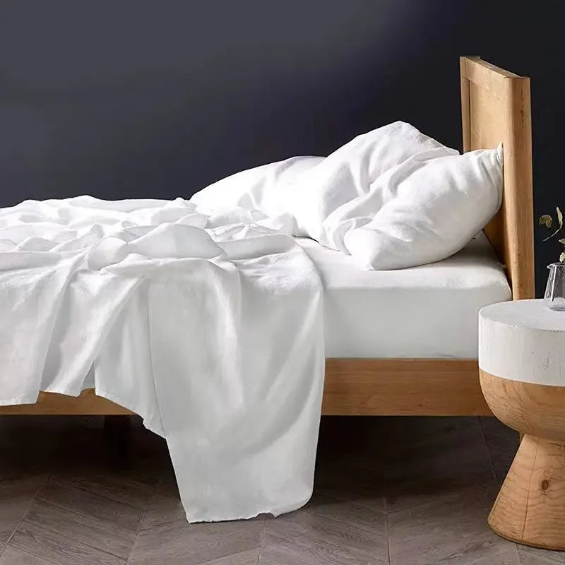 White pure linen bed sheet set with pillows draped on a wooden bed frame.
