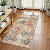 A vintage bohemian trellis runner rug with intricate floral patterns in shades of orange, blue, and cream on a wooden floor.