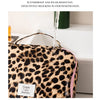 A leopard print toiletry bag is shown with water running over it, demonstrating its waterproof and wear-resistant features.