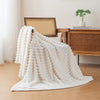 A fluffy white brushed flannel throw blanket draped on a wooden chair next to a desk.