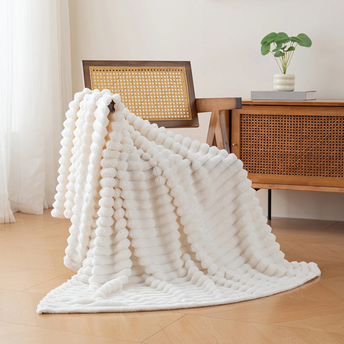 A fluffy white brushed flannel throw blanket draped on a wooden chair next to a desk.