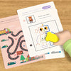 A hand is drawing lines on a magic tracing workbook which features a symmetric figure robot and various tracing exercises.