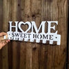 White wooden wall hooks shaped like the words HOME and SWEET HOME for home organization