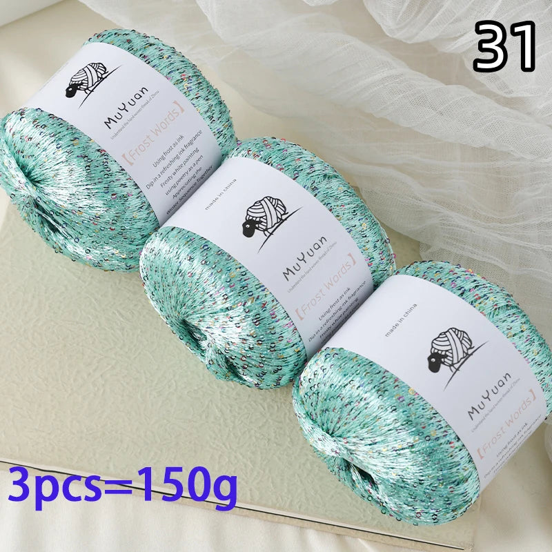 Three balls of teal glitter yarn labeled MuYuan Frost Words for knitting and crafting