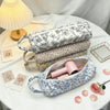 A light blue quilted cotton storage bag with a handle is shown next to various floral-patterned fabric items on a white table