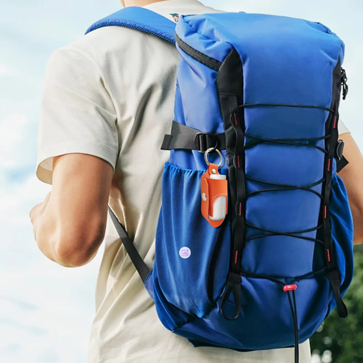 A person is wearing a blue backpack with an orange inhaler case attached to the strap.
