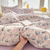 A close-up of a pink and blue floral dog print duvet cover set with pillows on a bed.