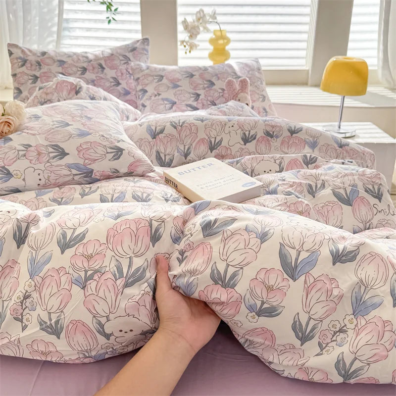 A close-up of a pink and blue floral dog print duvet cover set with pillows on a bed.