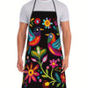 A man wearing a black floral print kitchen apron over a white t-shirt.
