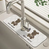 A silver kitchen faucet mounted on a white mat with a bear break design.