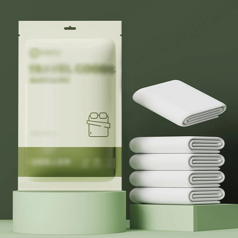 Un ensemble de draps pour lit double jetables blancs est exposé dans son emballage et empilé soigneusement.