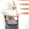 A woman wearing a white sweater is holding a grey insulated lunch bag with a brown strap.