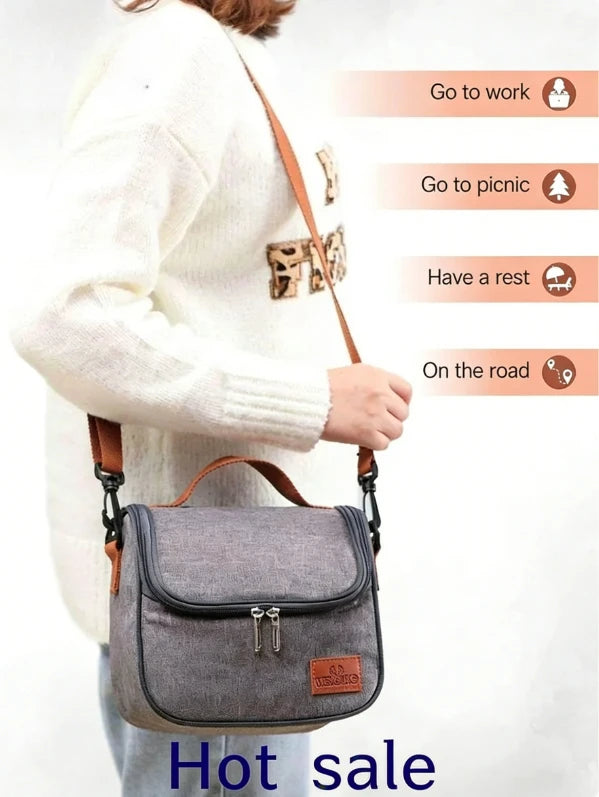 A woman wearing a white sweater is holding a grey insulated lunch bag with a brown strap.