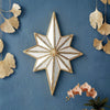 A geometric octagonal star wall mirror with gold trim mounted on a blue textured wall surrounded by gold leaf accents.