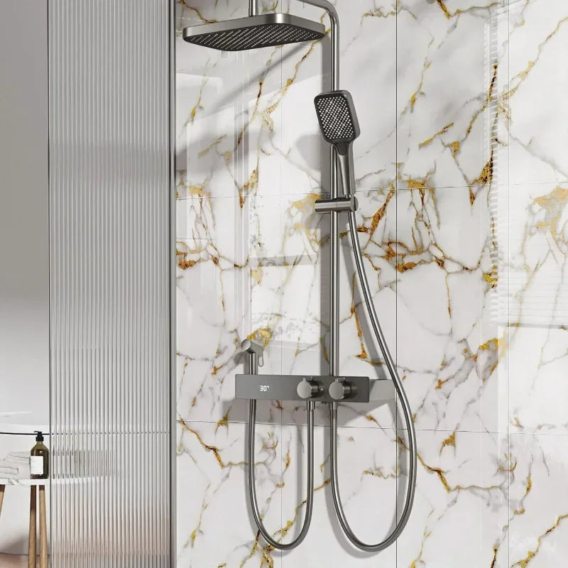 A modern silver shower system with a handheld shower head mounted on a marble-patterned wall.
