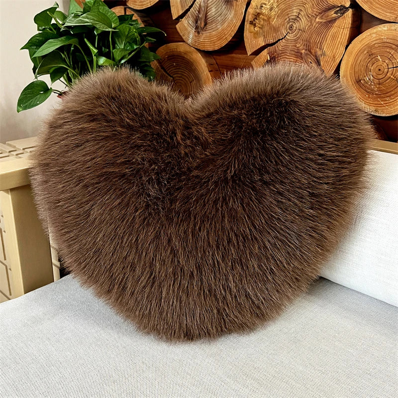 A fluffy, heart-shaped brown faux fur throw pillow resting on a light-colored sofa.