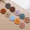A collection of round handmade PU leather labels in various earthy and muted tones arranged on a light wooden surface.