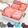 A collection of six colored laundry pouches and packing cubes are displayed in a white suitcase.