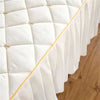 White quilted bed skirt with gold embroidery and gathered fabric detail