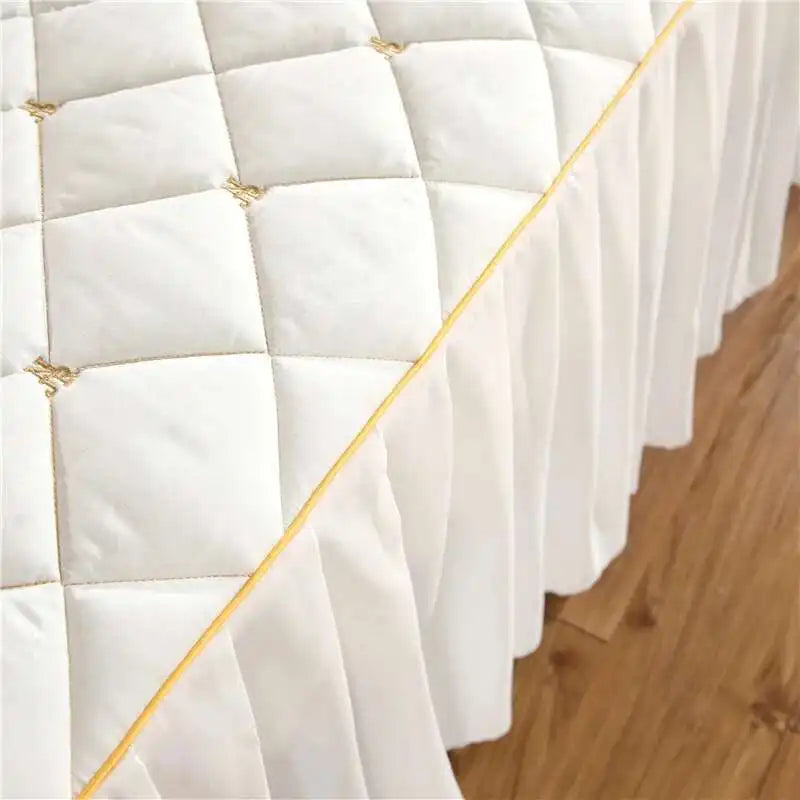 White quilted bed skirt with gold embroidery and gathered fabric detail
