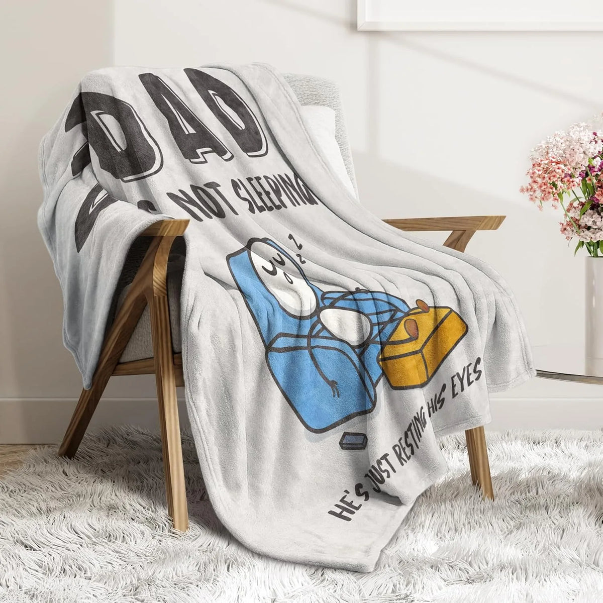 A gray fleece throw blanket featuring text about a dad not sleeping and resting his eyes on a blue object.