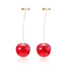 A pair of gold-toned pendant necklaces shaped like red cherries.
