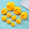 A collection of bright yellow plastic duck toys for babies scattered on a light blue surface.