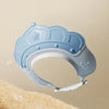 Light blue adjustable baby bath shampoo shield cap with ear protection shown against a beige background.