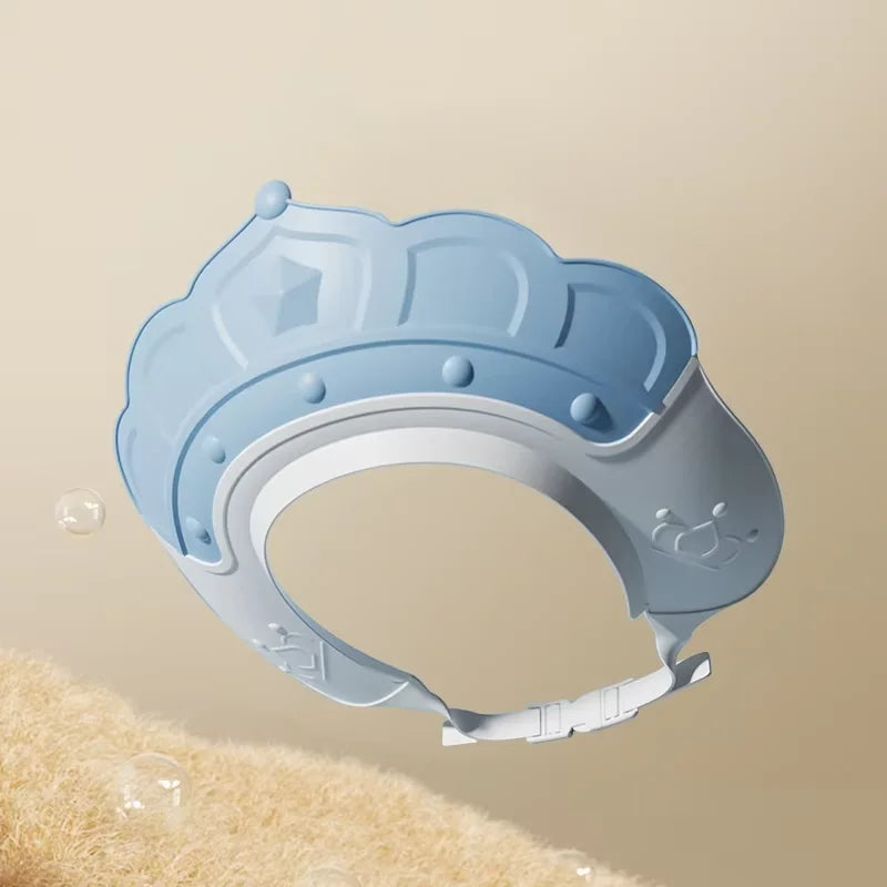 Light blue adjustable baby bath shampoo shield cap with ear protection shown against a beige background.
