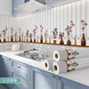 A kitchen splashback featuring white vertical stripes and decorative floral elements, with rolls of self-adhesive wallpaper v