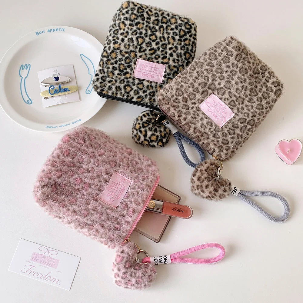A collection of leopard print cosmetic bags and a pink heart-shaped item displayed on a white surface.