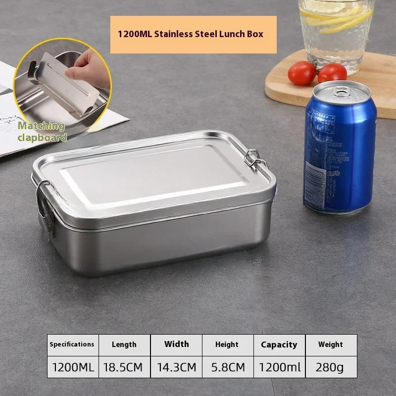 Une boîte à lunch en acier inoxydable argenté, à couvercle ouvert, à côté de tomates fraîches et d'un verre d'eau.