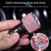 A hand holds a pink rhinestone crystal clear and dazzling product, likely a dual USB car charger.
